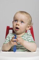 Baby boy holding spoon, studio shot - MUF001392