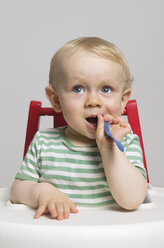 Baby boy holding spoon, studio shot - MUF001399