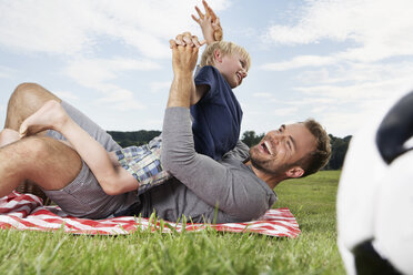 Germany, Cologne, Father and son playing around on picnic blanket - PDF000399