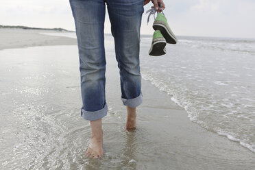 Deutschland, Niedersachsen, Ostfriesland, Langeoog, Beine einer Frau beim Spaziergang am Strand - JATF000307