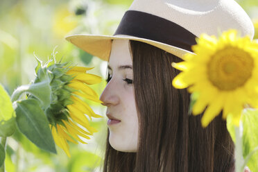 Germany, Cologne, young woman with hat and sunflower - JATF000331