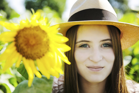 Deutschland, Köln, junge Frau mit Hut und Sonnenblume, lizenzfreies Stockfoto