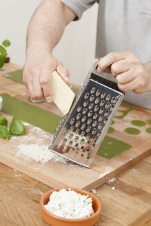 Mann bereitet grüne Ravioli mit Ricotta und geriebenem Parmesan zu - ECF000354