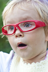 Germany, Schleswig-Holstein, Kiel, portrait of astonished little girl with red glasses - JFEF000224