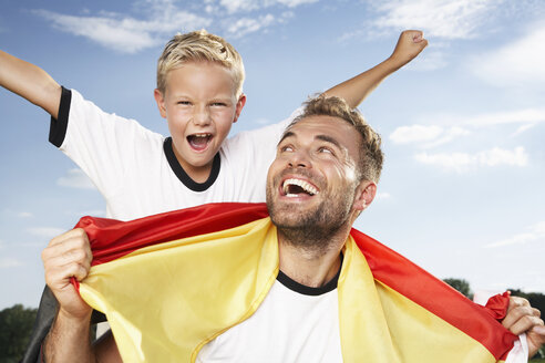 Germany, Cologne, Father and son cheering in football outfit - PDF000445