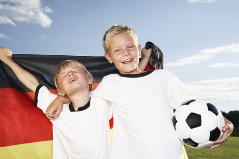 Germany, Cologne, Two boys wearing football shirts, holding German flag - PDF000453