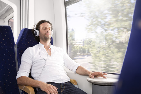 Mann mit Kopfhörern in einem Zug, lizenzfreies Stockfoto
