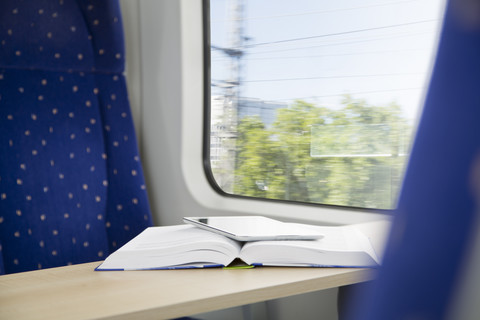 Buch und digitales Tablet in einem Zug, lizenzfreies Stockfoto