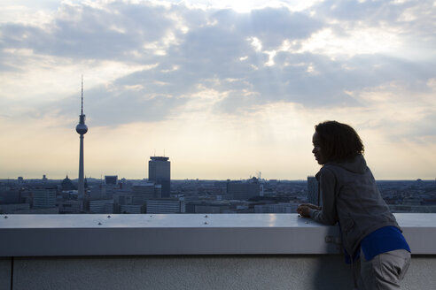 Deutschland, Berlin, Junge Frau auf Dachterrasse, Blick auf Aussicht - FKF000274