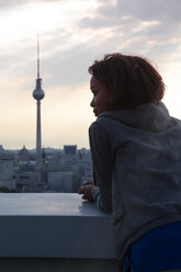 Germany, Berlin, Young woman on rooftop terrace, looking at view - FKF000273
