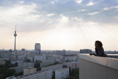 Deutschland, Berlin, Junge Frau auf Dachterrasse, Blick auf Aussicht - FKF000279