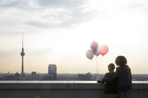 Germany, Berlin, Young women on rooftop terrace, holding balloons stock photo