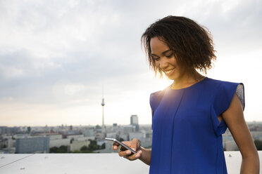 Germany, Berlin, Young woman using mobile phone - FKF000268