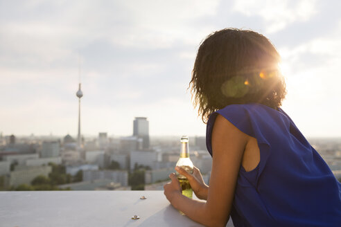 Deutschland, Berlin, Junge Frau mit Blick, hält Bierflasche - FKF000289