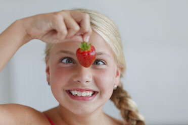 Smiling blond girl looking at strawberry - HR000010