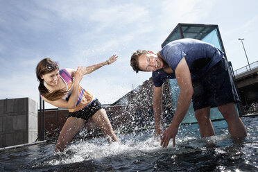 Germany, Bavaria, Munich, Couple splashing with water at fountain - RBF001352