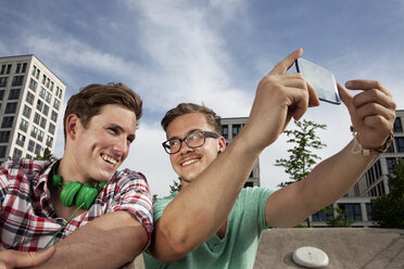 Germany, Bavaria, Munich, Two friends with smartphone taking self-portrait - RBF001361