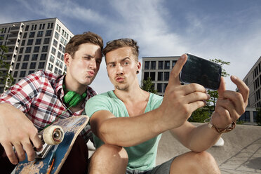 Deutschland, Bayern, München, Zwei Freunde mit Smartphone beim Selbstporträt - RBF001362