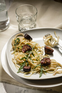 Teller mit Feigen-Tagliatelle, Rucola, Sauce und einem Glas Wasser, Studioaufnahme - SBDF000223