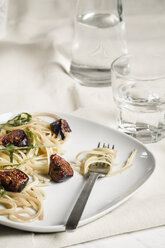 Teller mit Feigen-Tagliatelle, Rucola, Sauce und einem Glas Wasser, Studioaufnahme - SBDF000224