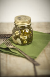 Eingelegte und in Scheiben geschnittene Jalapeno-Chilis (Capsicum annuum) in einem Glas, grüne Serviette und Gabel, Studioaufnahme - SBDF000228