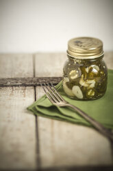 Eingelegte und in Scheiben geschnittene Jalapeno-Chilis (Capsicum annuum) in einem Glas, grüne Serviette und Gabel, Studioaufnahme - SBDF000229