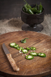 Sliced Jalapeno-Chilis (Capsicum annuum) on a chopping board, studio shot - SBD000242