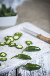 Geschnittene und ganze Jalapeno-Chilis (Capsicum annuum) auf einem Brett, Studioaufnahme - SBDF000244