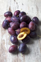 Plums (Prunus domestica) on wooden table, studio shot - CSF020109