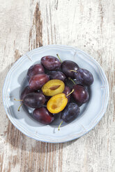 Plate with plums (Prunus domestica) on wooden table, studio shot - CSF020112