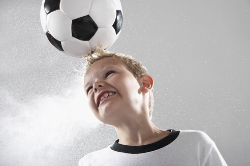 Junge im Fußballtrikot köpft Ball - PDF000497