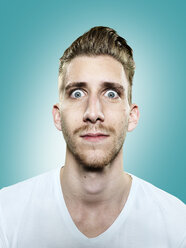 Portrait of young man with eyes wide open, studio shot - STKF000356