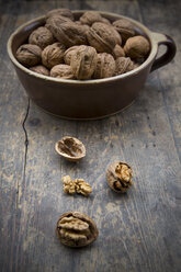 Earthenware bowl with walnuts (Juglans regia) on wooden table, studio shot - LVF000223