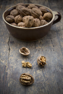 Steingutschale mit Walnüssen (Juglans regia) auf Holztisch, Studioaufnahme - LVF000223