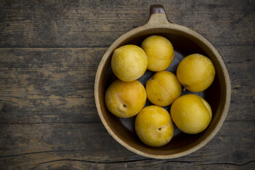 Yellow plums in ceramic bowl on wooden table, studio shot - LV000239