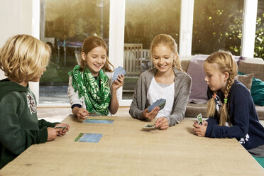 Vier Kinder spielen ein Kartenspiel im Wohnzimmer - GDF000219