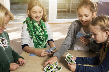 Vier Kinder spielen ein Kartenspiel im Wohnzimmer - GDF000220