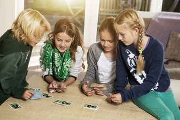 Vier Kinder spielen ein Kartenspiel im Wohnzimmer - GDF000221