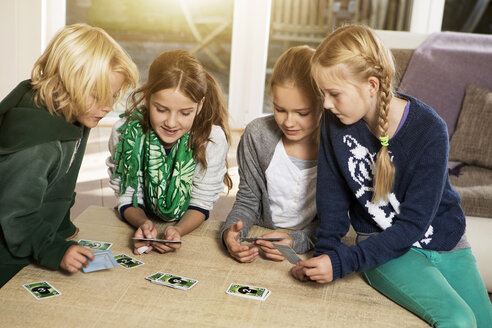 Four children playing card game in living room - GDF000221