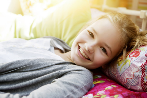 Lächelndes Mädchen auf dem Bett liegend, Porträt, lizenzfreies Stockfoto