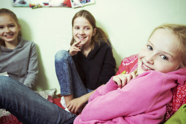 Drei lächelnde Mädchen auf dem Bett - GDF000240
