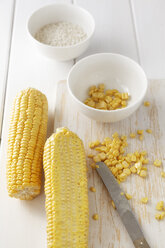 Maiskolben, Maiskörner und Arborio-Reis auf weißem Holztisch, Studioaufnahme - EVGF000245
