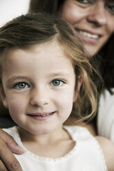 Porträt eines kleinen Mädchens mit ihrer Mutter im Hintergrund - JATF000386