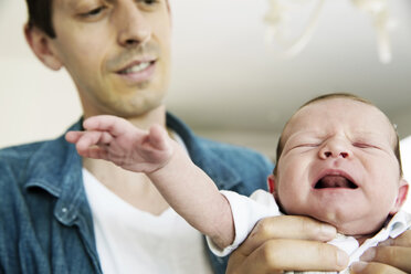 Young father holding his crying newborn son - JATF000389