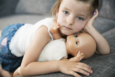 Porträt eines kleinen Mädchens, das mit seiner Puppe auf dem Sofa liegt, Nahaufnahme - JATF000391