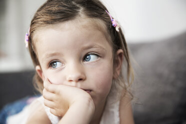 Sad looking little girl lying on sofa, close-up - JATF000395