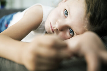 Traurig aussehendes kleines Mädchen auf dem Sofa liegend, Nahaufnahme - JATF000433
