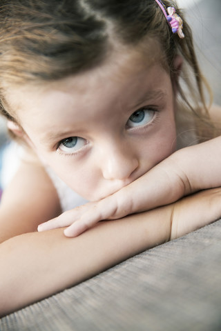 Traurig aussehendes kleines Mädchen auf dem Sofa liegend, Nahaufnahme, lizenzfreies Stockfoto