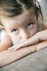 Sad looking little girl lying on sofa, close-up - JATF000396