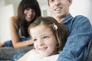 Junge Eltern mit kleiner Tochter sitzen zu Hause auf dem Sofa - JATF000398